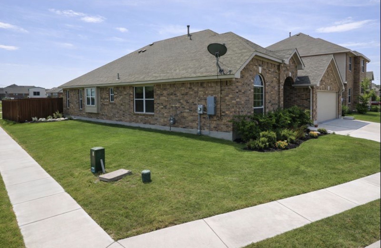 1052 Hot Spring Valley Buda, TX 78610 - Photo 33 of 36 View of side of property featuring brick siding, a shingled roof, and driveway