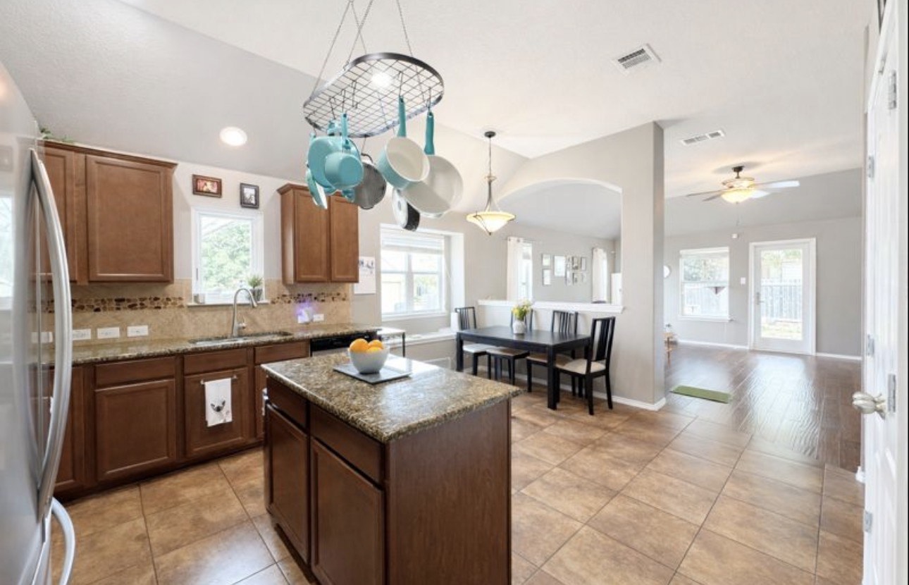 1052 Hot Spring Valley Buda, TX 78610 - Photo 6 of 36 Kitchen with freestanding refrigerator, a center island, hanging light fixtures, light tile patterned flooring, and tasteful backsplash