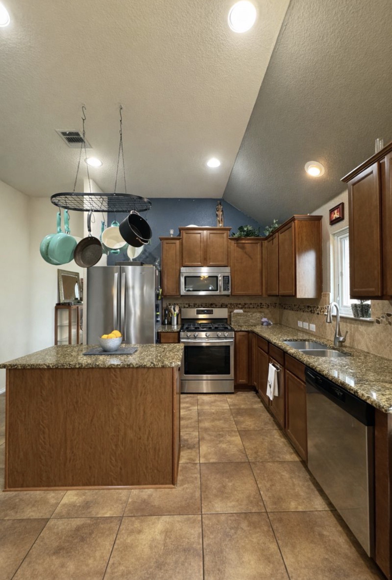 1052 Hot Spring Valley Buda, TX 78610 - Photo 7 of 36 Kitchen with appliances with stainless steel finishes, a kitchen island, light stone countertops, a textured ceiling, and decorative backsplash
