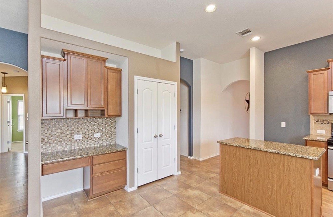 1052 Hot Spring Valley Buda, TX 78610 - Photo 8 of 36 Kitchen with arched walkways, decorative backsplash, light stone counters, a kitchen island, and recessed lighting