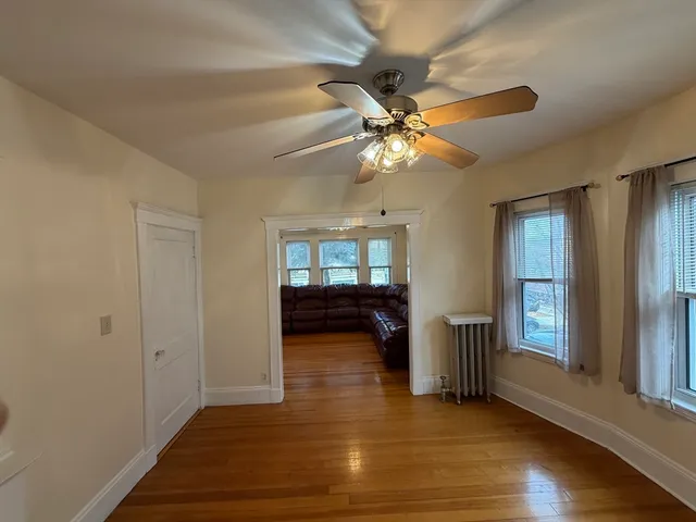 a view of empty room with wooden floor and fan