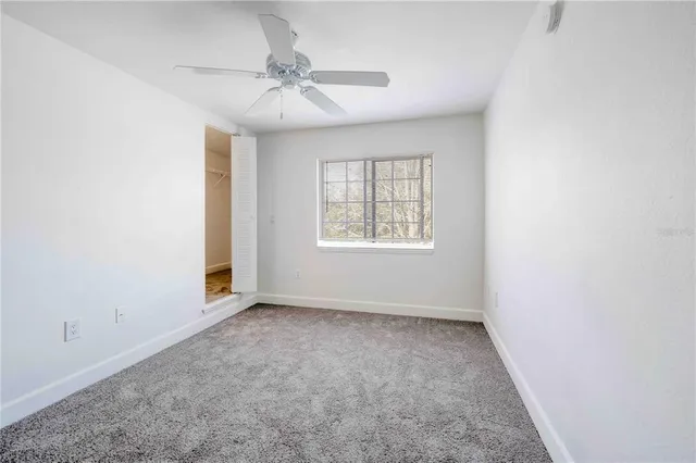 an empty room with windows and fan