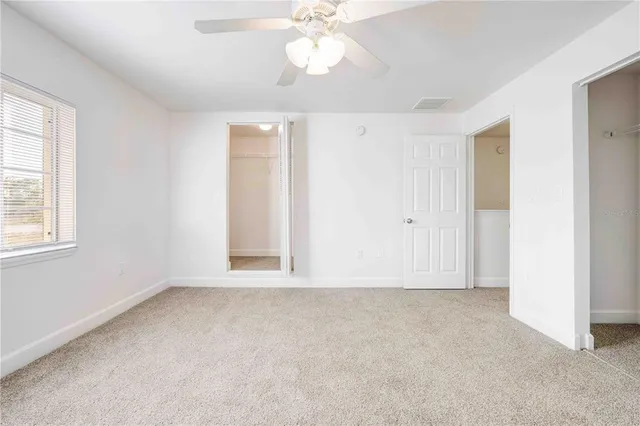 an empty room with windows and ceiling fan