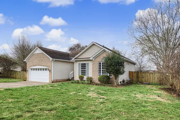 a view of a house with a yard and a large tree