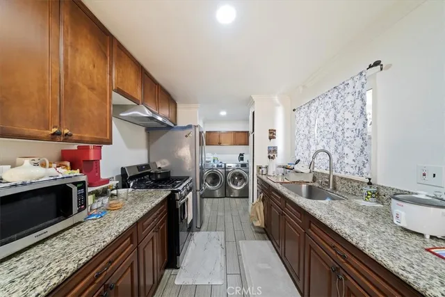 a kitchen with stainless steel appliances granite countertop a sink stove and refrigerator