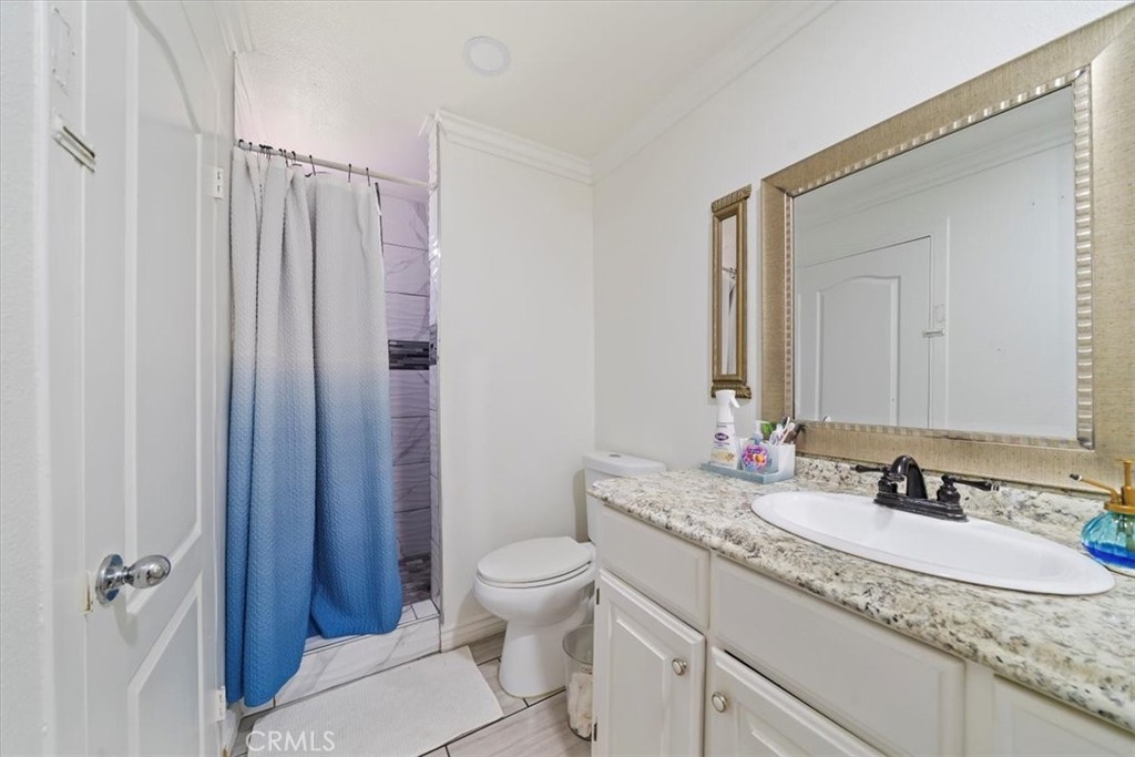 250 North Linden Avenue, Unit 327 Rialto, CA 92376 - Photo 20 of 27 a bathroom with a granite countertop sink a toilet a mirror and shower