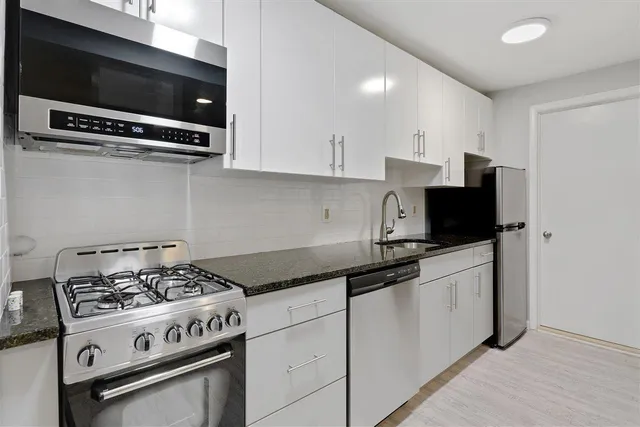 a kitchen with granite countertop a stove and a microwave