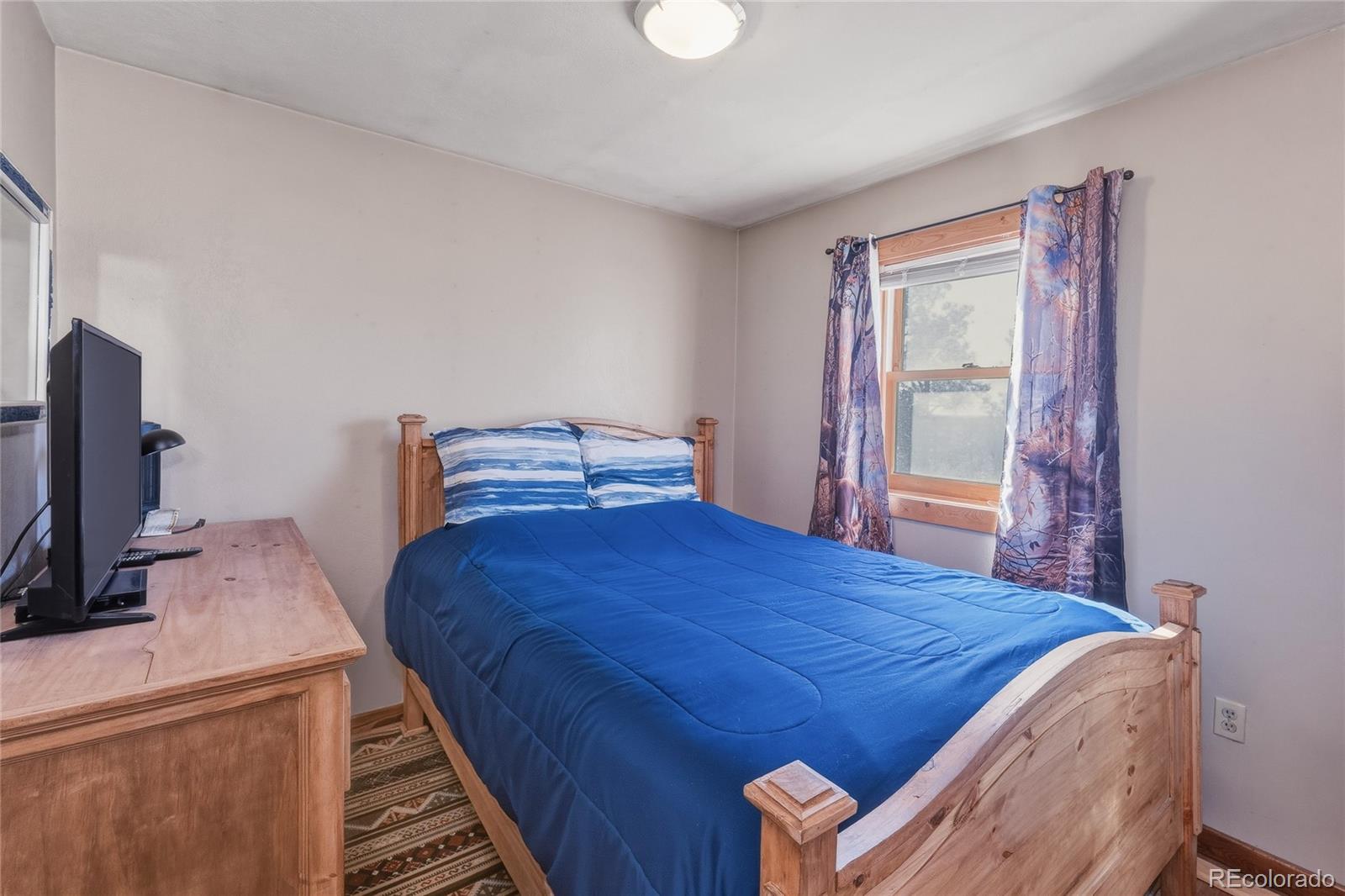 13240 Big Pine Ridge Road Weston, CO 81091 - Photo 11 of 49 a bedroom with a bed and a flat tv screen on a dresser