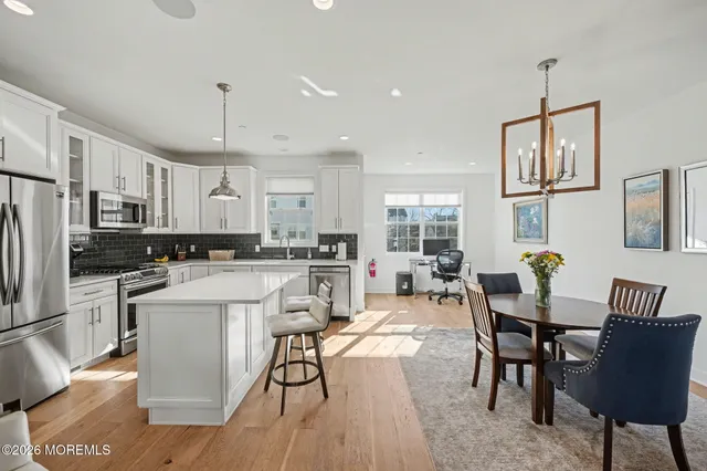 a kitchen with stainless steel appliances a dining table chairs refrigerator and sink