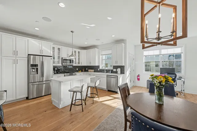 a kitchen with stainless steel appliances granite countertop a dining table chairs refrigerator and microwave