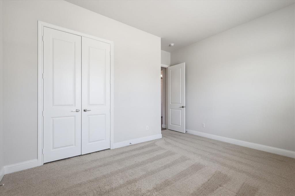 4017 Alpine Street Midlothian, TX 76065 - Photo 26 of 37 Neutral-toned room featuring a double-door closet with brushed nickel hardware, light gray walls, and plush patterned carpeting