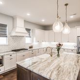 a kitchen with stainless steel appliances granite countertop a sink a stove a refrigerator and island with wooden floor