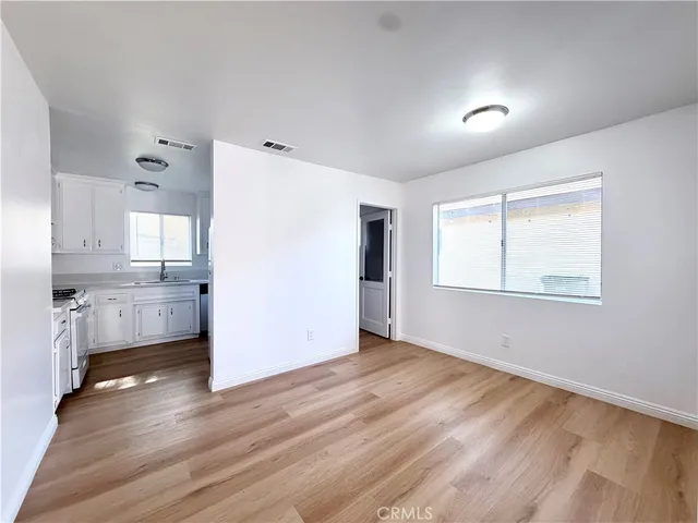 a view of an empty room with a window and wooden floor