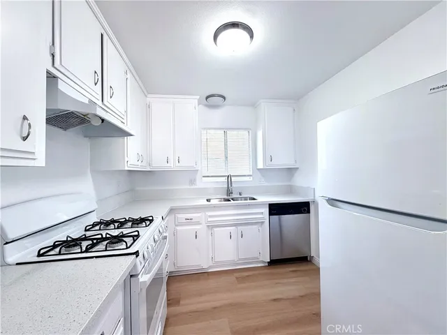 a kitchen with stainless steel appliances a sink a stove a refrigerator and cabinets