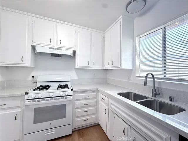 a kitchen with white cabinets white stainless steel appliances and sink