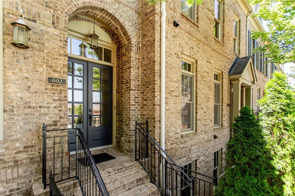 Charming covered entry way boasting brick detail and transom glass doors.