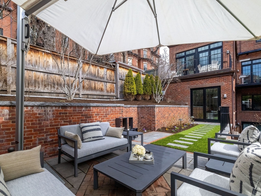 5 Joy Street, Unit 1 Boston, MA 02108 - Photo 15 of 32 a view of a patio with couches table and chairs under an umbrella