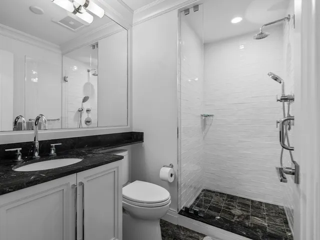 a bathroom with a granite countertop sink a toilet and a mirror