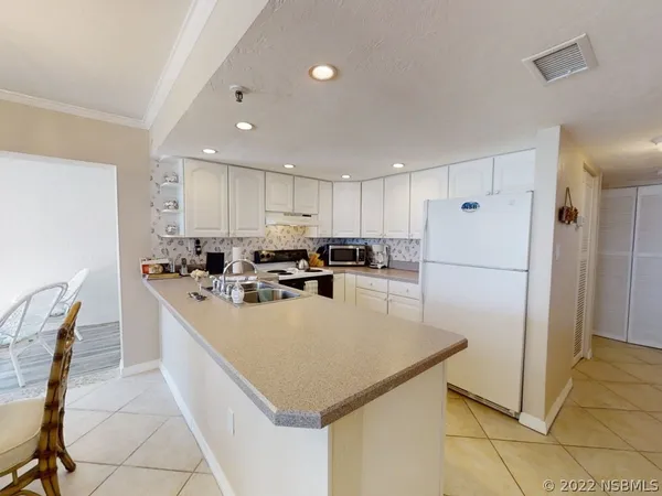 a kitchen with a sink a refrigerator and white cabinets