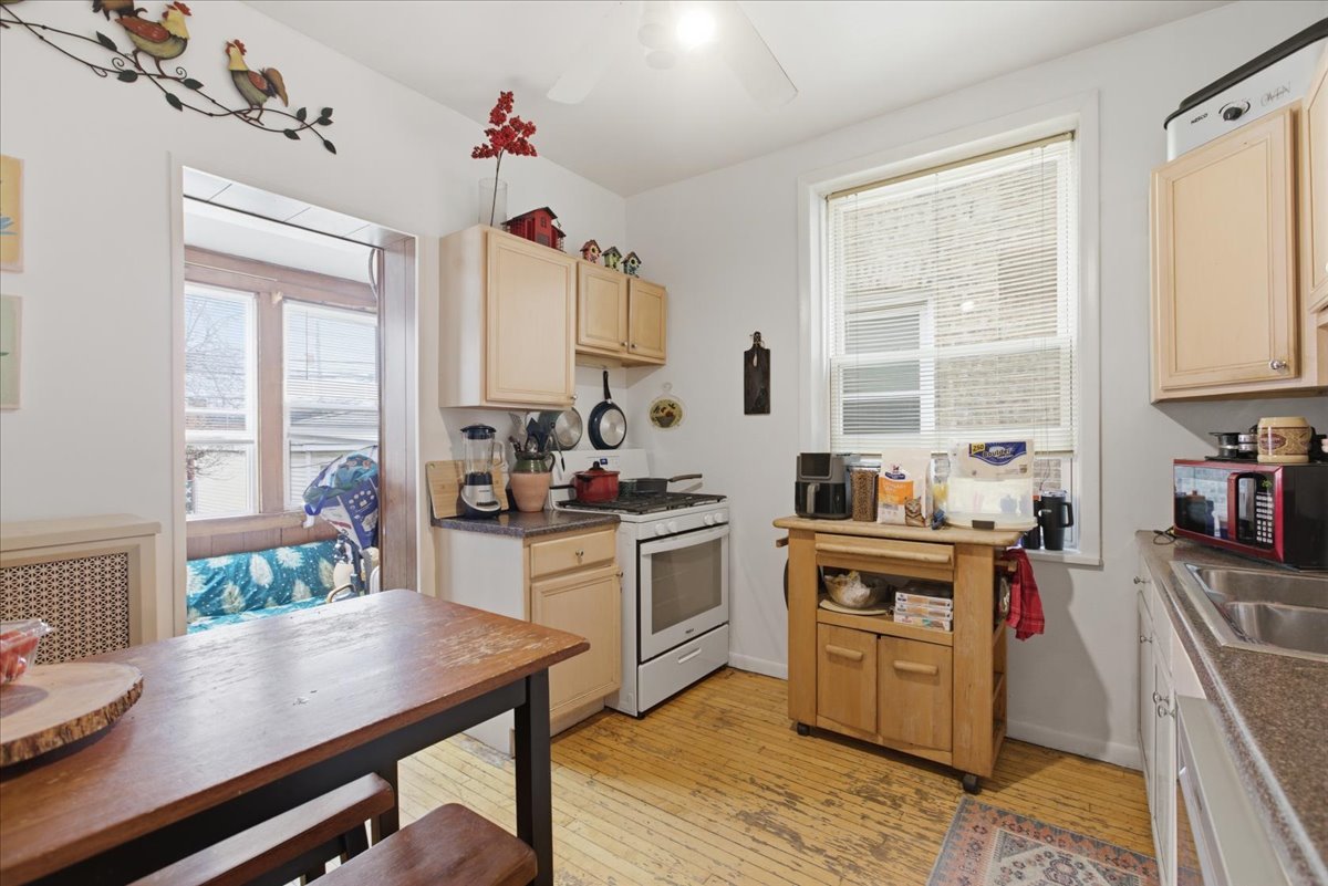 2318 West Addison Street Chicago, IL 60618 - Photo 23 of 31 a kitchen with a stove a sink dishwasher a dining table and chairs with wooden floor