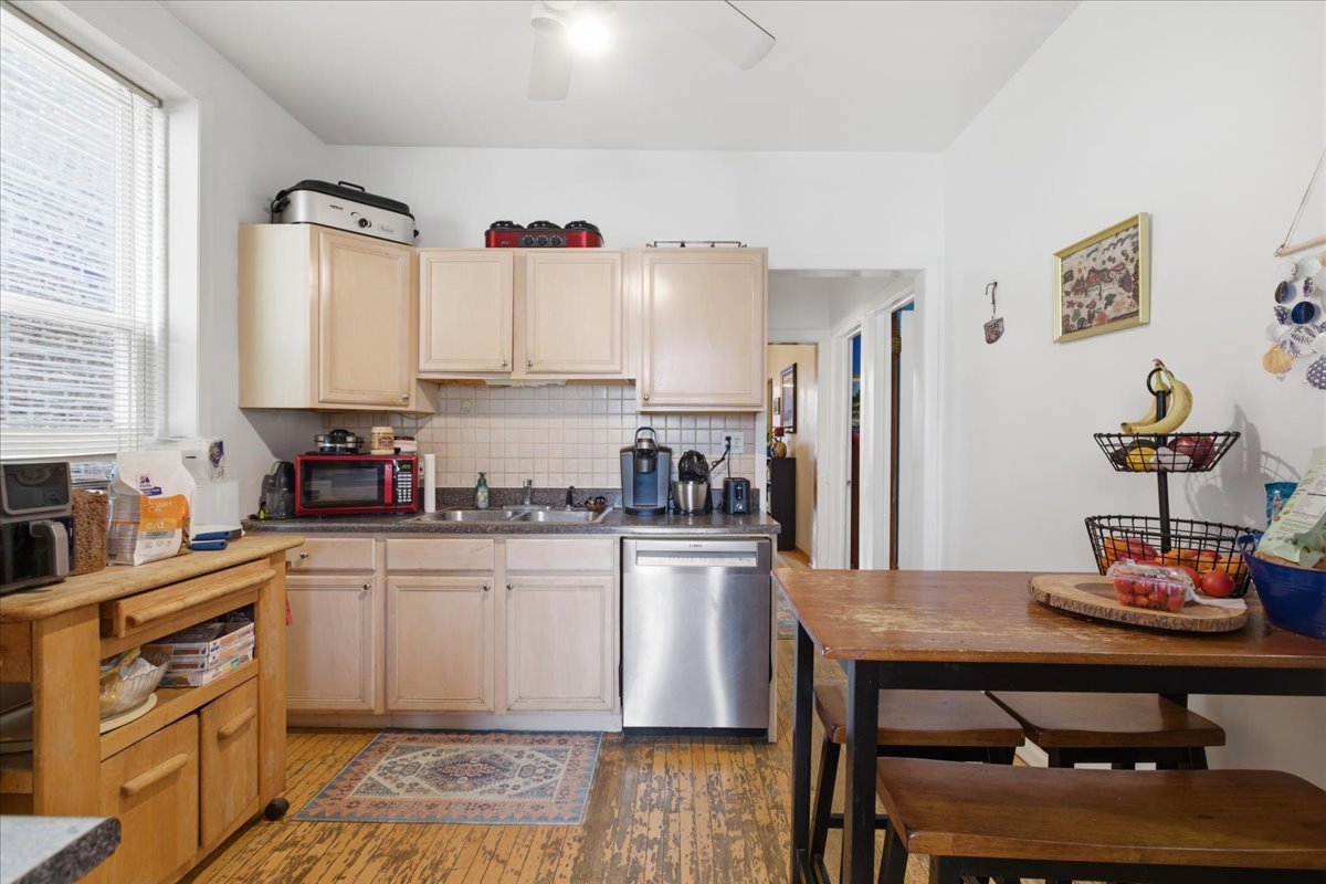 2318 West Addison Street Chicago, IL 60618 - Photo 25 of 31 a kitchen with a dining table cabinets appliances and wooden floor