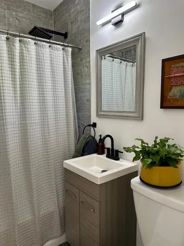 a bathroom with a sink a toilet and shower
