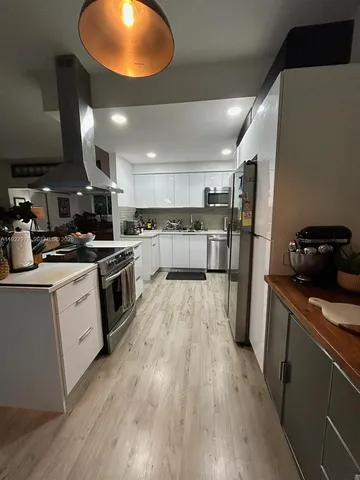 a kitchen with stainless steel appliances granite countertop a stove a refrigerator a sink and a microwave oven with wooden floor