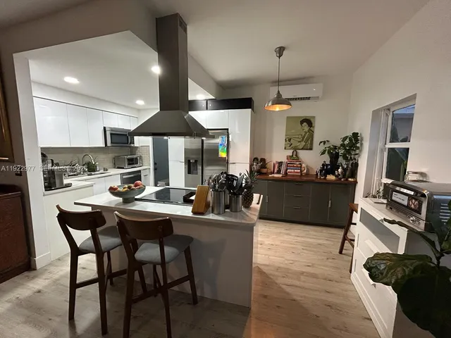 a view of a dining room and livingroom with furniture wooden floor a rug a painting and a chandelier
