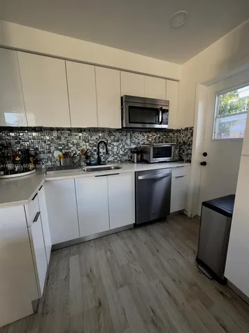 a kitchen with stainless steel appliances a sink a stove top oven a refrigerator a counter space and cabinets