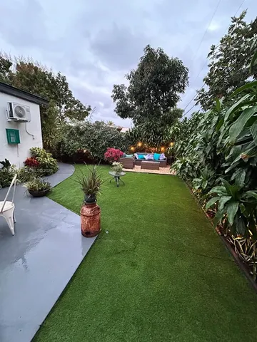 a garden with a bench in front of the house