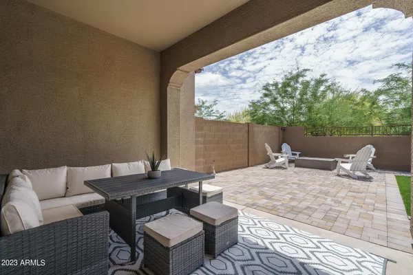 a view of a patio with chairs and floor to ceiling window next to a yard