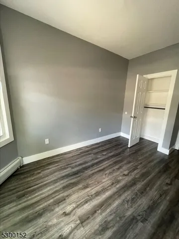 an empty room with wooden floor and windows with curtains