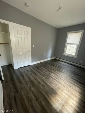 a view of an empty room with wooden floor & closet