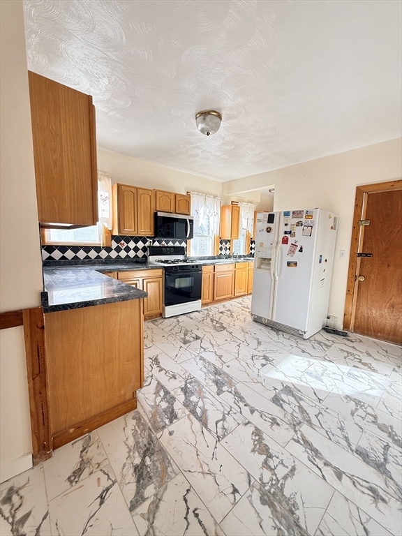 a kitchen with stainless steel appliances granite countertop a stove refrigerator and a sink