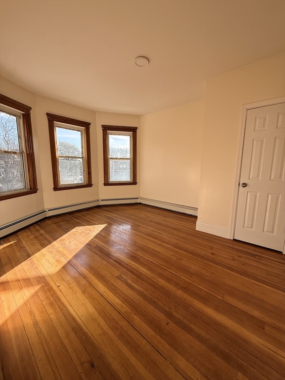 253 Norfolk Street, Unit 3 Boston, MA 02124 - Photo 4 of 14 a view of an empty room with wooden floor and a window