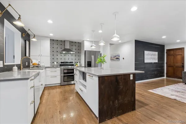 a kitchen with stainless steel appliances kitchen island granite countertop a stove a sink and a refrigerator