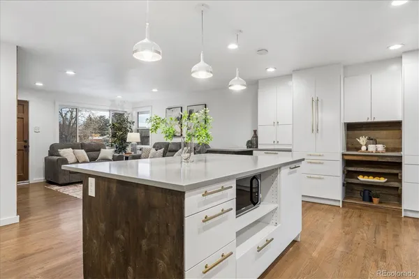 a kitchen with kitchen island granite countertop appliances cabinets and a wooden floor