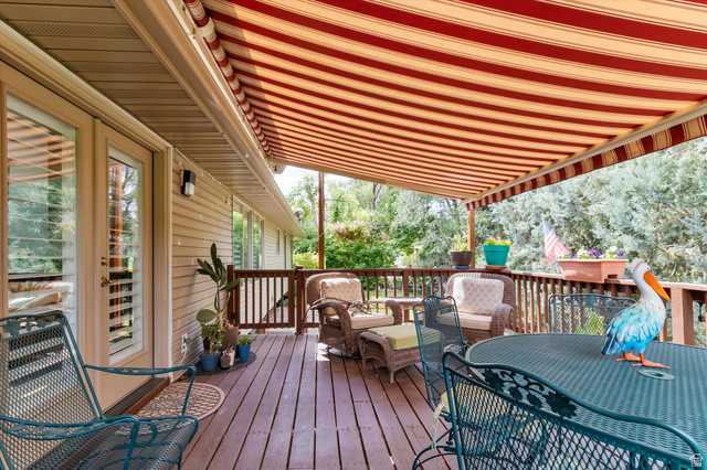 2863 Fallentine Road Sandy, UT 84093 - Photo 9 of 48 Expansive outdoor deck featuring wood-finish flooring, a retractable striped awning, wood railing, and direct access to interior spaces via French doors