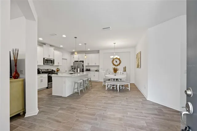 a living room with stainless steel appliances furniture a dining table and kitchen view
