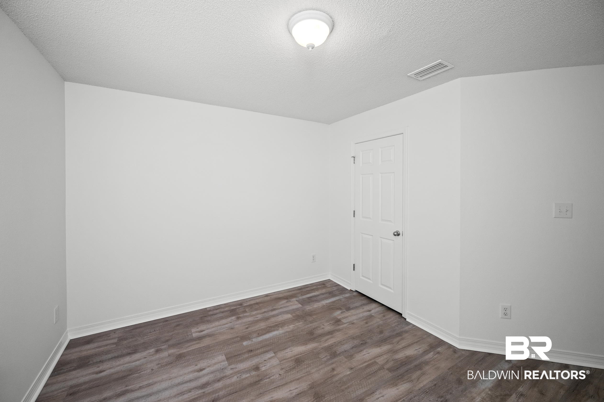 306 Monteith Oaks Drive Foley, AL 36535 - Photo 22 of 38 Unfurnished room featuring dark wood-type flooring and a textured ceiling