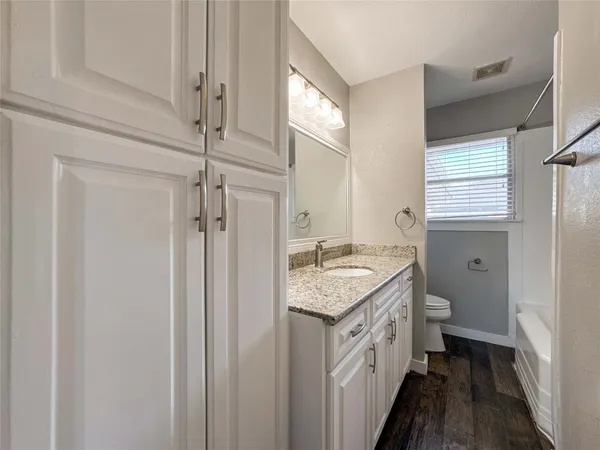 a bathroom with a granite countertop sink and a toilet