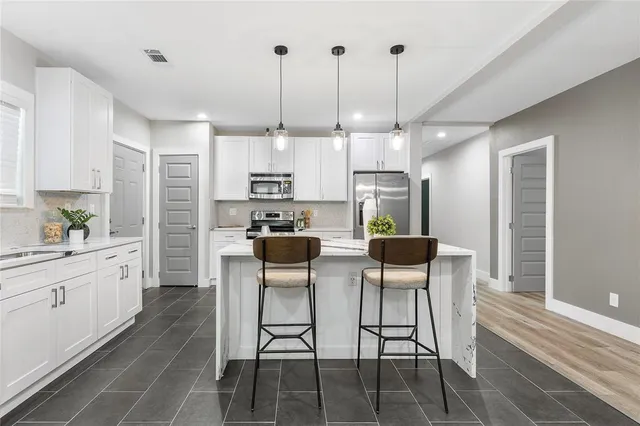 a kitchen with stainless steel appliances kitchen island granite countertop a table chairs and white cabinets