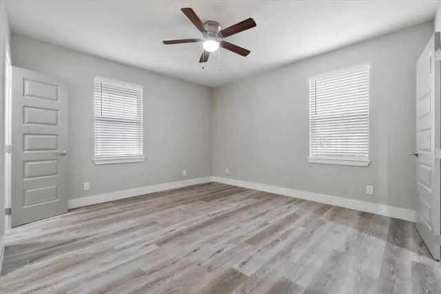 a view of empty room with wooden floor and fan