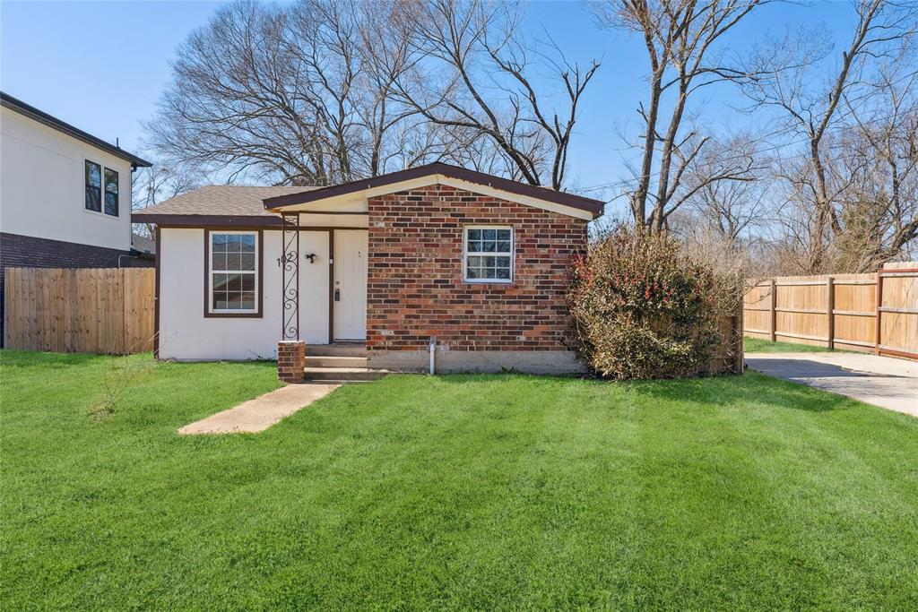 View of front of property with brick siding, fence, and a front yard