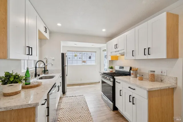 a kitchen with stainless steel appliances kitchen island wooden floors and white cabinets