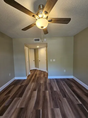 a view of a room with a ceiling fan and wooden floor