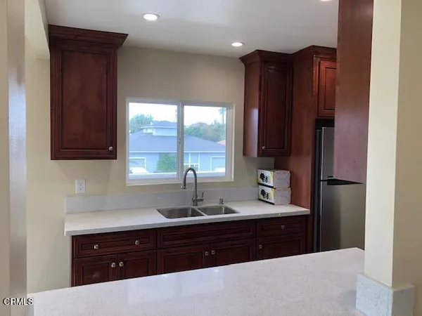 a kitchen with a sink wooden cabinets and a window