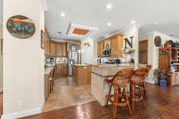 a kitchen with stainless steel appliances granite countertop a stove top oven a sink a dining table and chairs with wooden floor