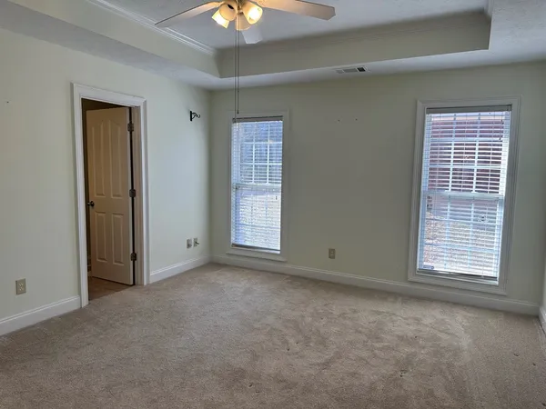 an empty room with windows and chandelier fan