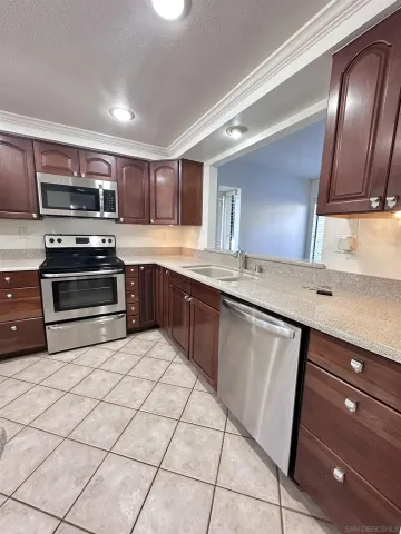 a kitchen with stainless steel appliances granite countertop a sink and stove top oven with wooden cabinets
